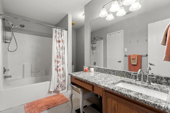 Full bath with shower / bath combo with shower curtain, vanity, a textured ceiling, tile patterned flooring, and toilet | Image 19