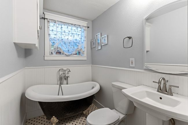 Full bathroom featuring wainscoting, a freestanding tub, toilet, and a sink | Image 11