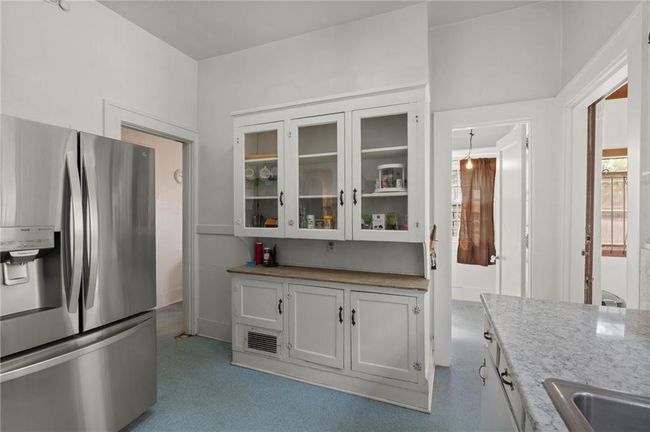 Kitchen featuring glass insert cabinets, white cabinetry, a sink, and stainless steel fridge. | Image 12