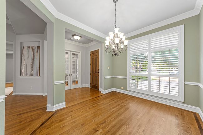 Spare room featuring a chandelier, wood finished floors, baseboards, french doors, and ornamental molding | Image 9