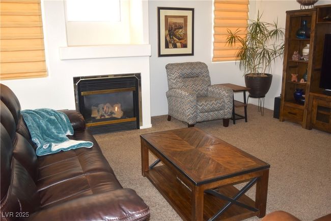 Carpeted living area featuring a glass covered fireplace and baseboards | Image 17
