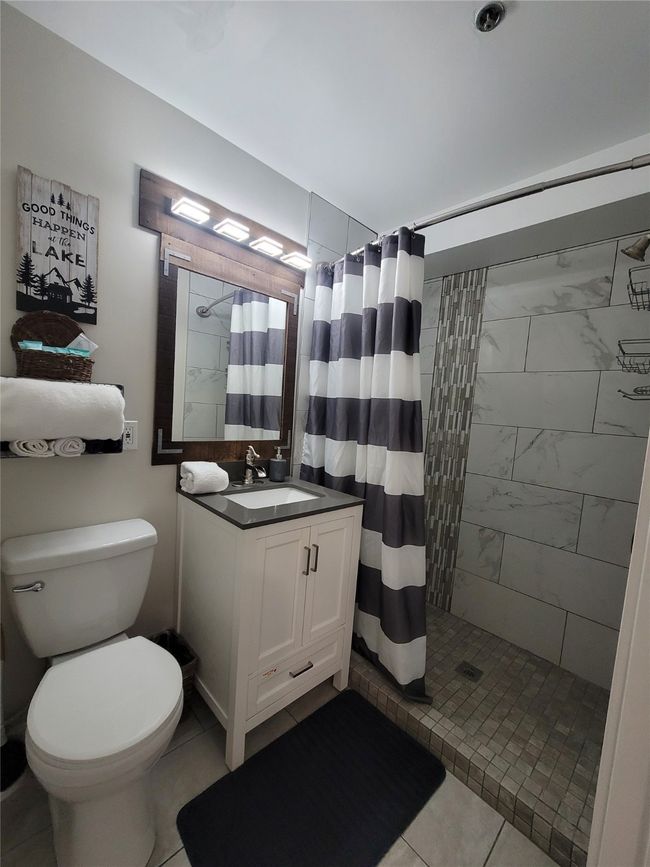 Bathroom featuring toilet, vanity, tile patterned floors, and curtained shower | Image 12