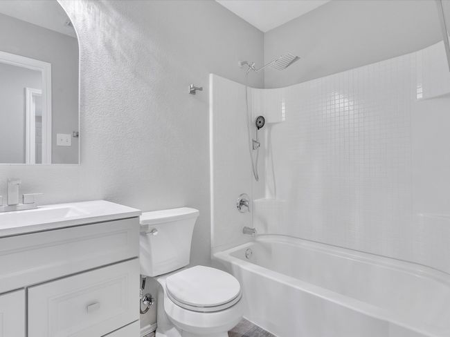 Full bathroom featuring bathtub / shower combination, toilet, vanity, and a textured wall | Image 18
