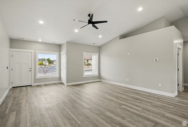 Unfurnished living room with a ceiling fan, wood finished floors, recessed lighting, baseboards, and vaulted ceiling | Image 11