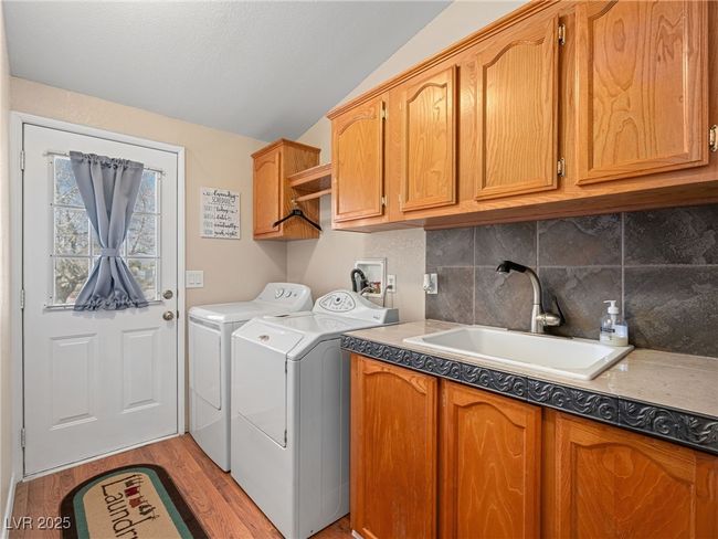 Laundry area with a sink, cabinet space, light wood-style floors, and washing machine and dryer | Image 39