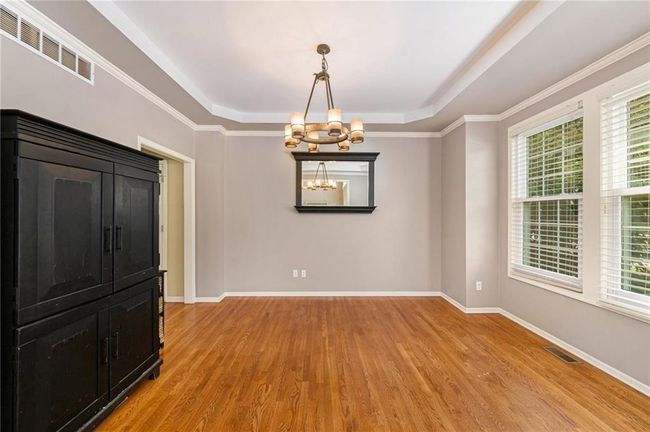 Unfurnished room featuring a raised ceiling, light wood-style flooring, a chandelier, and plenty of natural light | Image 6