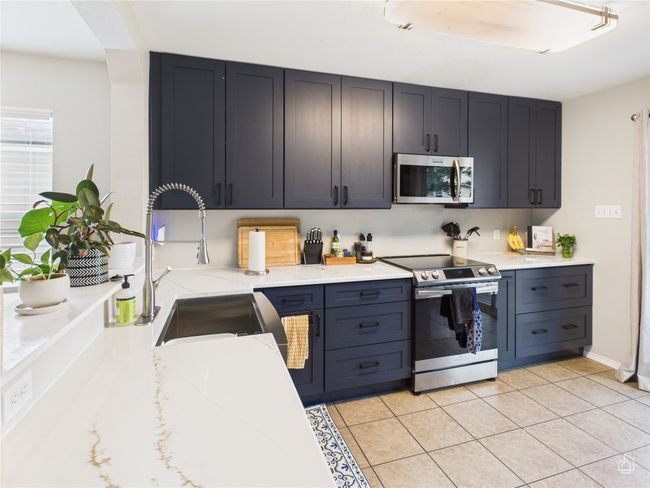 Kitchen featuring stainless steel appliances, light stone countertops, light tile patterned flooring, and arched walkways | Image 8