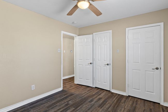 Unfurnished bedroom with ceiling fan, dark wood-style flooring, and baseboards | Image 18