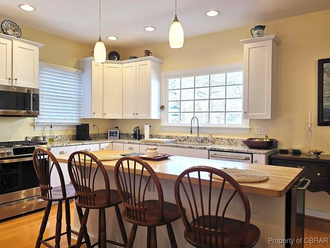 Kitchen featuring white cabinetry, recessed lighting, a kitchen breakfast bar, and appliances with stainless steel finishes | Image 22