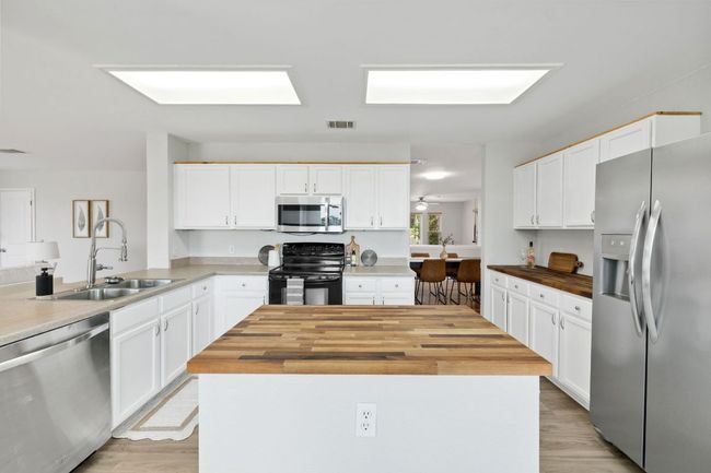 Kitchen featuring appliances with stainless steel finishes, butcher block counters, a sink, and white cabinets | Image 15
