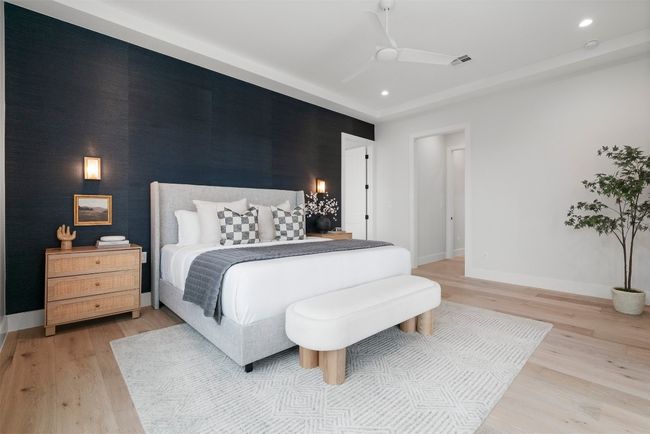 With doors leading directly to the backyard, the primary bedroom offers a seamless connection to outdoor living, complemented by a dramatic accent wall, high tray ceiling, and thoughtfully placed recessed lighting to elevate the entire space | Image 18