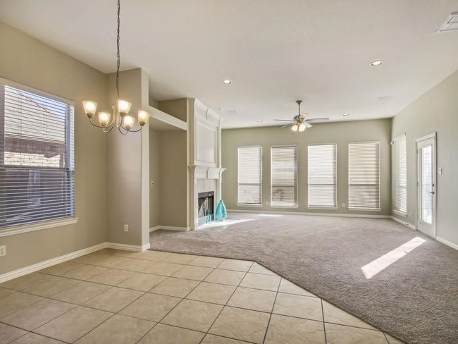 Unfurnished living room with light colored carpet, light tile patterned floors, a large fireplace, a chandelier, and ceiling fan | Image 8