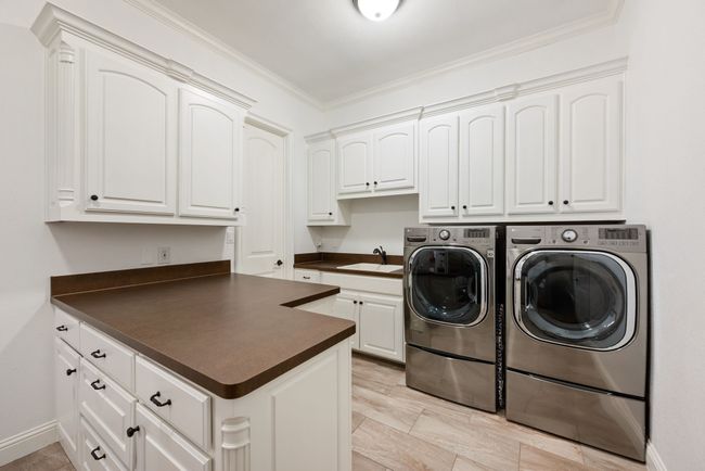 There's lots of space in this fabulous laundry room which includes tile flooring, multiple cabinets, a sink and space for an additional refrigerator. It is accessible through 3 different entries: the living area, the garage, and the Primary Bedroom closet. | Image 16