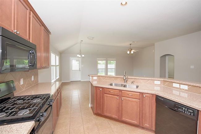 A view of the kitchen showing the beautiful granite counters open to the dining and family room areas. | Image 10