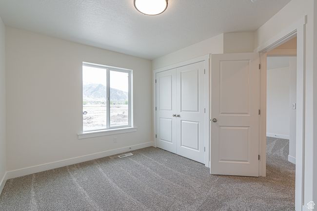 Unfurnished bedroom with carpet flooring, a mountain view, and a closet | Image 14