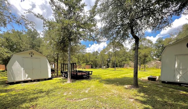 View of green lawn featuring a storage shed and view of scattered trees | Image 4