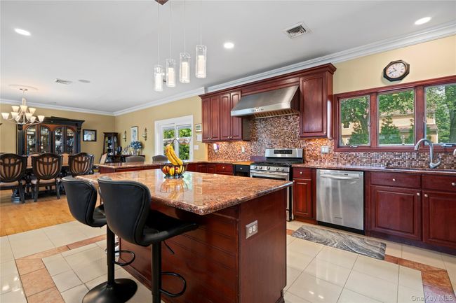 Kitchen with ornamental molding, light tile patterned flooring, a kitchen bar, pendant lighting, and tasteful backsplash | Image 8