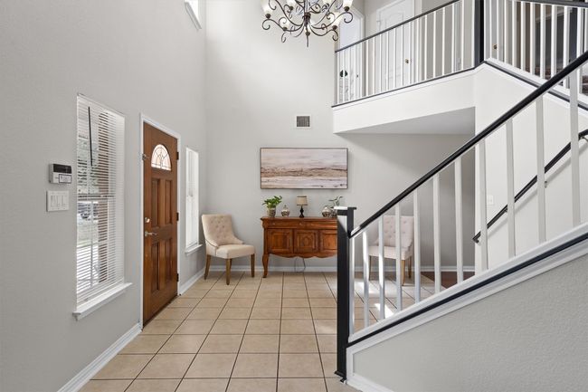 Step inside to a grand two-story foyer with an elegant chandelier and wood railing staircase that immediately sets the tone. | Image 7
