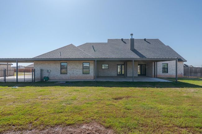 Rear view of house featuring a yard, a patio, roof with shingles, fence, and brick siding | Image 33