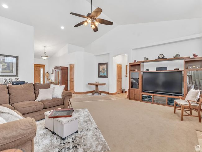 Living room with high vaulted ceiling, ceiling fan, arched walkways, light colored carpet, and recessed lighting | Image 9