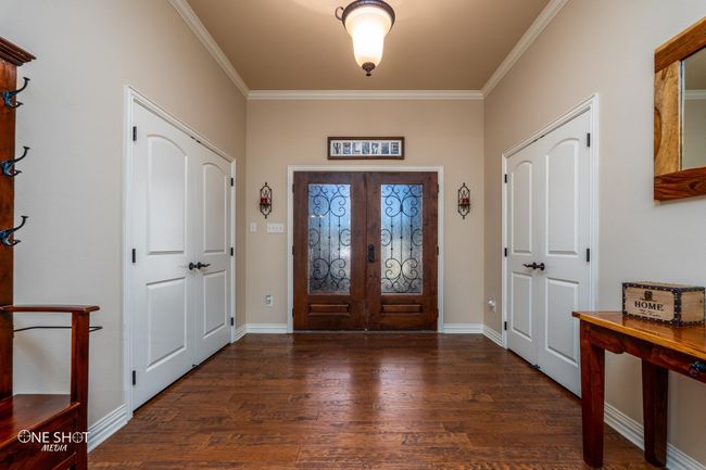 Foyer entrance with french doors, wood finished floors, crown molding, and baseboards | Image 7