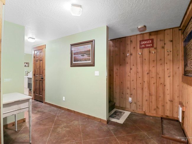 Hall with wood walls, a textured ceiling, and dark tile patterned flooring | Image 36