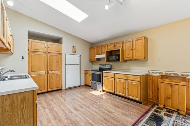 Tons of beautiful oak cabinets and a skylight complete this big kitchen | Image 16