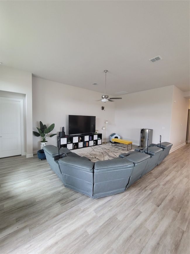 Living room with a ceiling fan, baseboards, visible vents, and wood finished floors | Image 6
