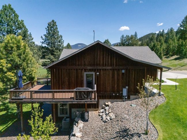 Rear view of house featuring a deck, a lawn, a shingled roof, and central AC unit | Image 60