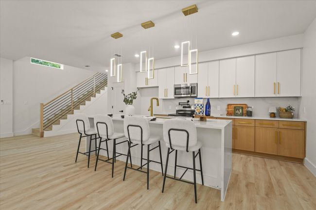 Kitchen featuring stainless steel appliances, light wood finished floors, a center island with sink, a breakfast bar, and recessed lighting | Image 4