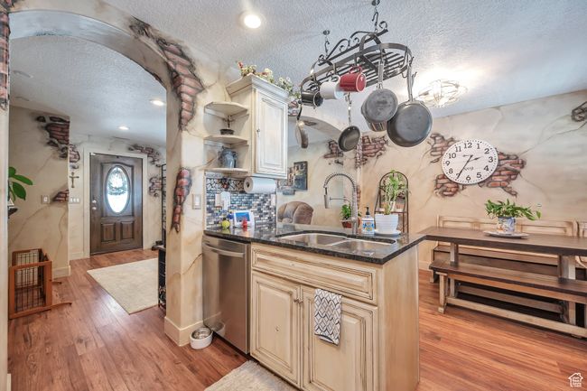 Kitchen with light wood finished floors, a sink, open shelves, stainless steel dishwasher, and a textured ceiling | Image 12