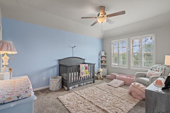 Carpeted bedroom featuring a nursery area, baseboards, and a ceiling fan | Image 29
