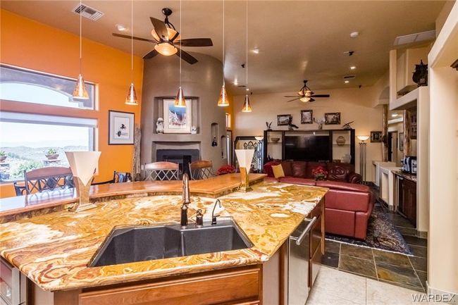 Kitchen featuring ceiling fan, open floor plan, light stone countertops, a fireplace, and pendant lighting | Image 34