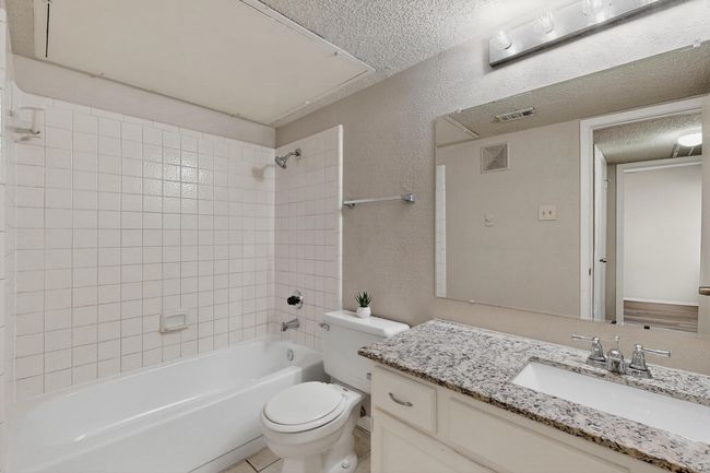 Bathroom featuring a textured wall, a textured ceiling, vanity, and shower / tub combination | Image 25