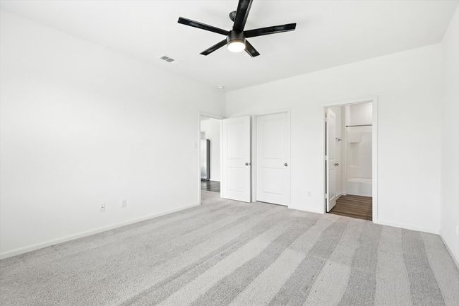 Unfurnished bedroom with carpet flooring, ensuite bathroom, and a ceiling fan | Image 12