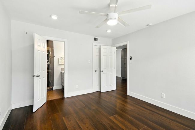 Unfurnished bedroom featuring dark wood finished floors, ensuite bathroom, recessed lighting, and a ceiling fan | Image 10