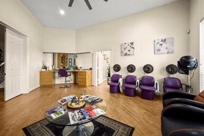 This room is currently set up as a hair salon with multiple styling chairs, hair washing stations, and a hair dryer station. It features wood flooring, a high ceiling with a fan, and is well-lit. The space could be easily converted to suit various other purposes depending on your needs. | Image 18
