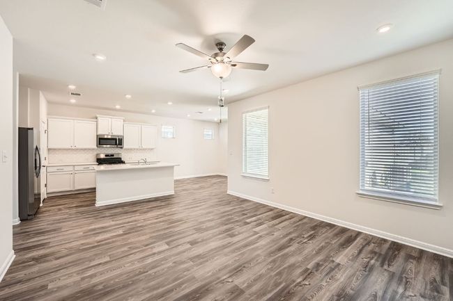 Kitchen featuring backsplash, baseboards, ceiling fan, open floor plan, and stainless steel appliances | Image 7