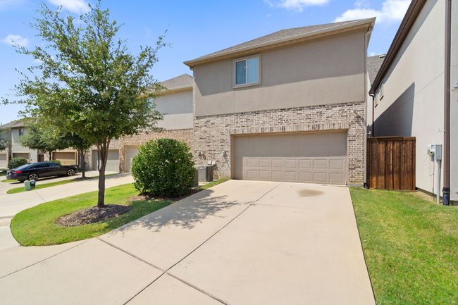 View of front of house featuring stucco siding, driveway, an attached garage, and brick siding | Image 26