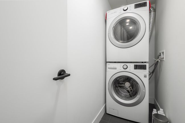 Laundry area with estacked washer and dryer and dark tile patterned floors | Image 19