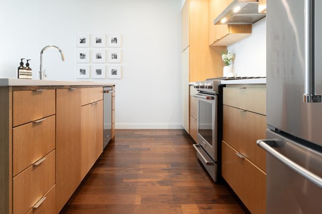 Kitchen featuring light countertops, baseboards, appliances with stainless steel finishes, dark wood-style floors, and ventilation hood | Image 11