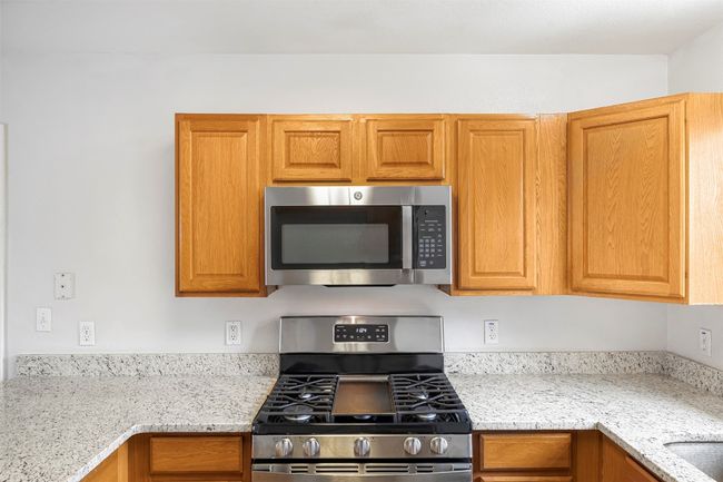 Kitchen featuring stainless steel appliances and light stone countertops | Image 13