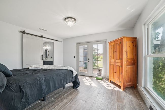 Primary bedroom featuring a barn door, access to exterior, french doors, and tile flooring | Image 15