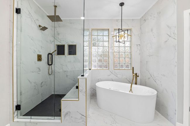 The newly remodeled primary bathroom has a separate shower with a seat and a soaking tub. | Image 17