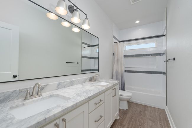 Full bath featuring a sink, toilet, double vanity, and wood finished floors | Image 30
