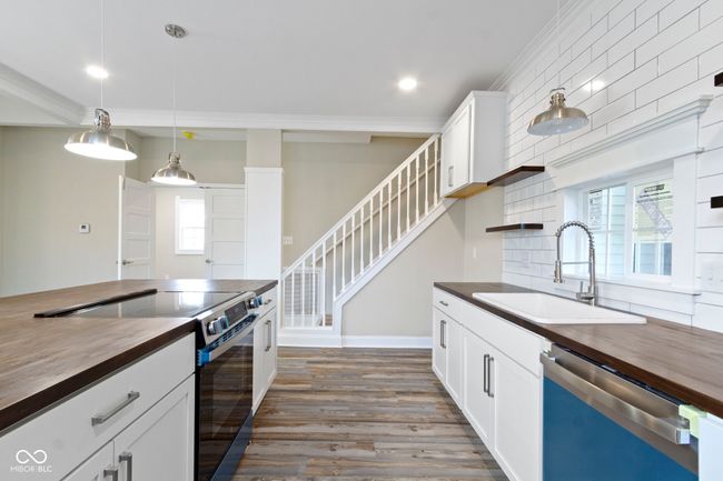 kitchen with wood counters, appliances with stainless steel finishes, a sink, dark wood finished floors, and tasteful backsplash | Image 16