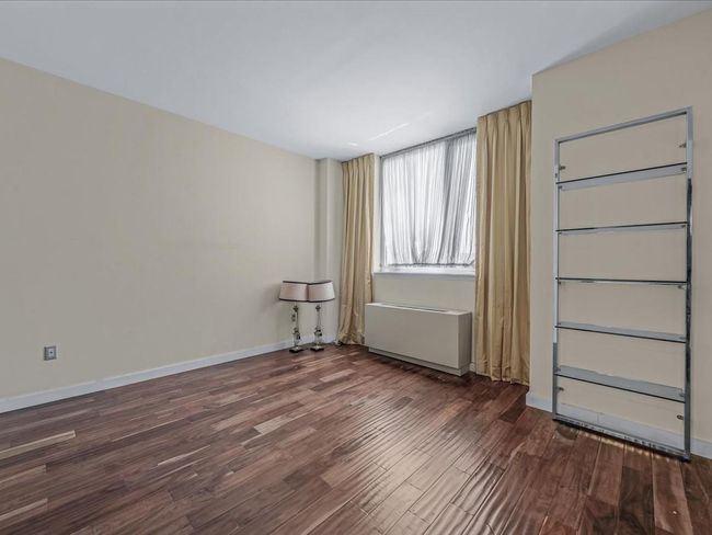 Spare room featuring dark wood-style floors and radiator heating unit | Image 8