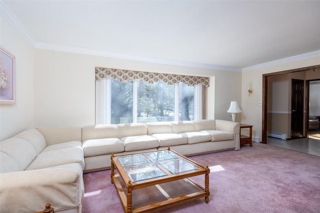 Carpeted living room featuring ornamental molding and a baseboard radiator | Image 10