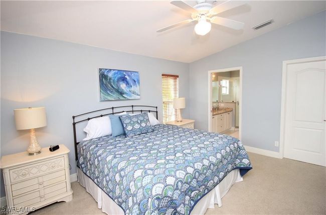 Carpeted bedroom with lofted ceiling, connected bathroom, and ceiling fan | Image 11