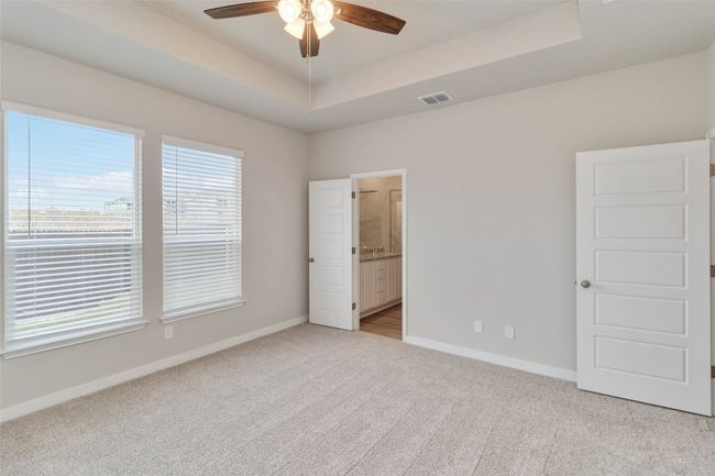 Unfurnished bedroom with visible vents, a tray ceiling, baseboards, and light colored carpet | Image 29